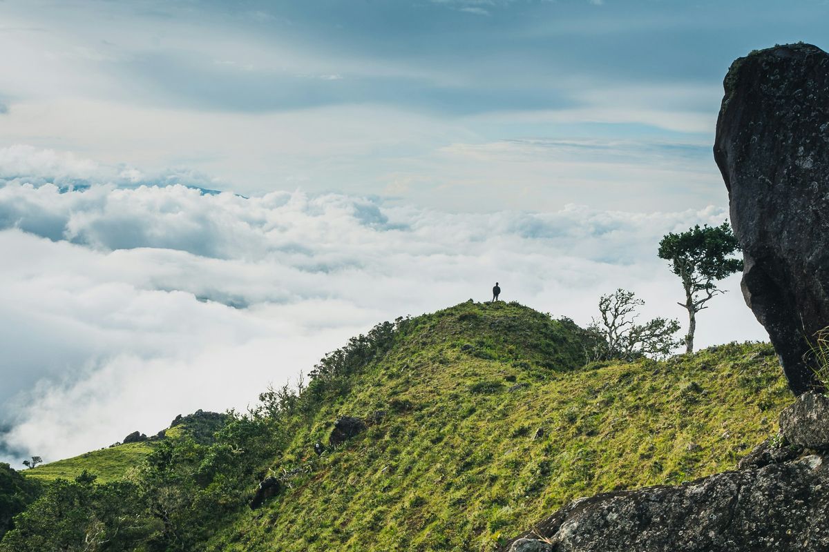 A hiker on a green ridge above the clouds near Boquete